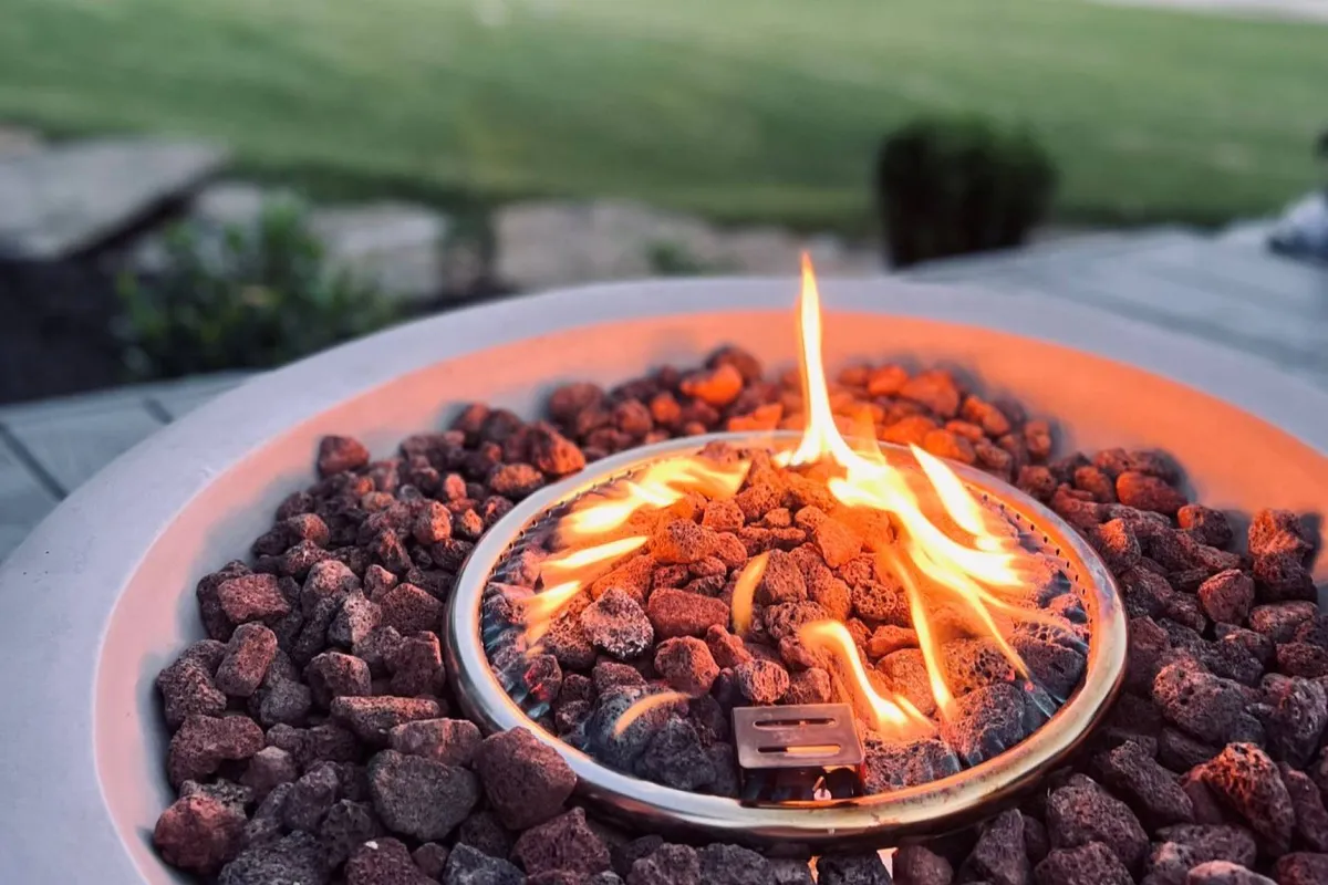 A cozy fire pit glows against an outdoor landscape, suggesting moments of togetherness and warmth under the stars. The scene invites thoughts of evening conversations and shared experiences with friends or a loved one.